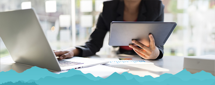 Woman using laptop and tablet to review tax forms